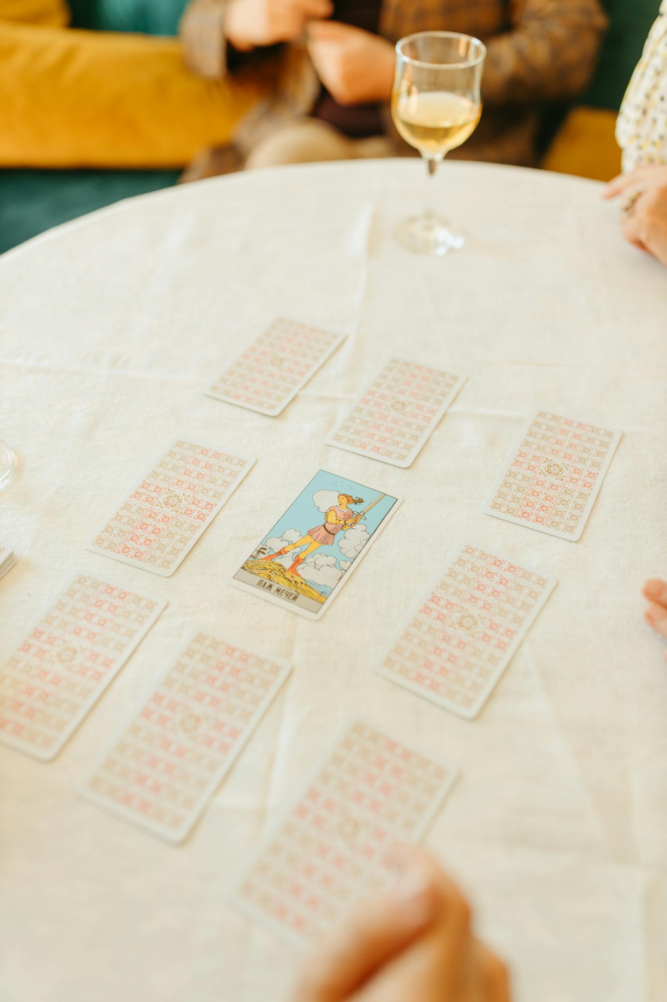 A group gathers around a table for a tarot card reading with a glass of wine.